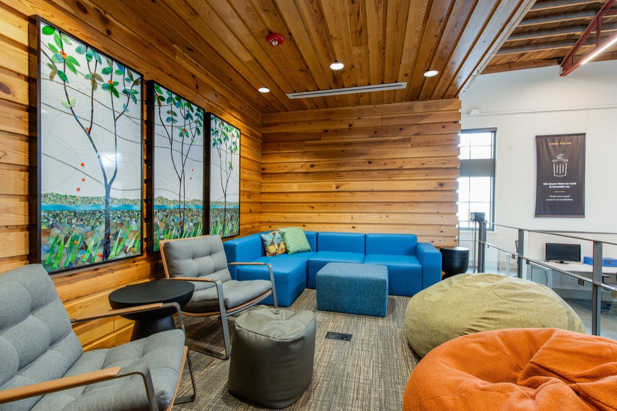 The Inglewood room, lined in wood reclaimed from the auditorium floor, with three stained-glass tree panels on the wall and a blue modular sofa.